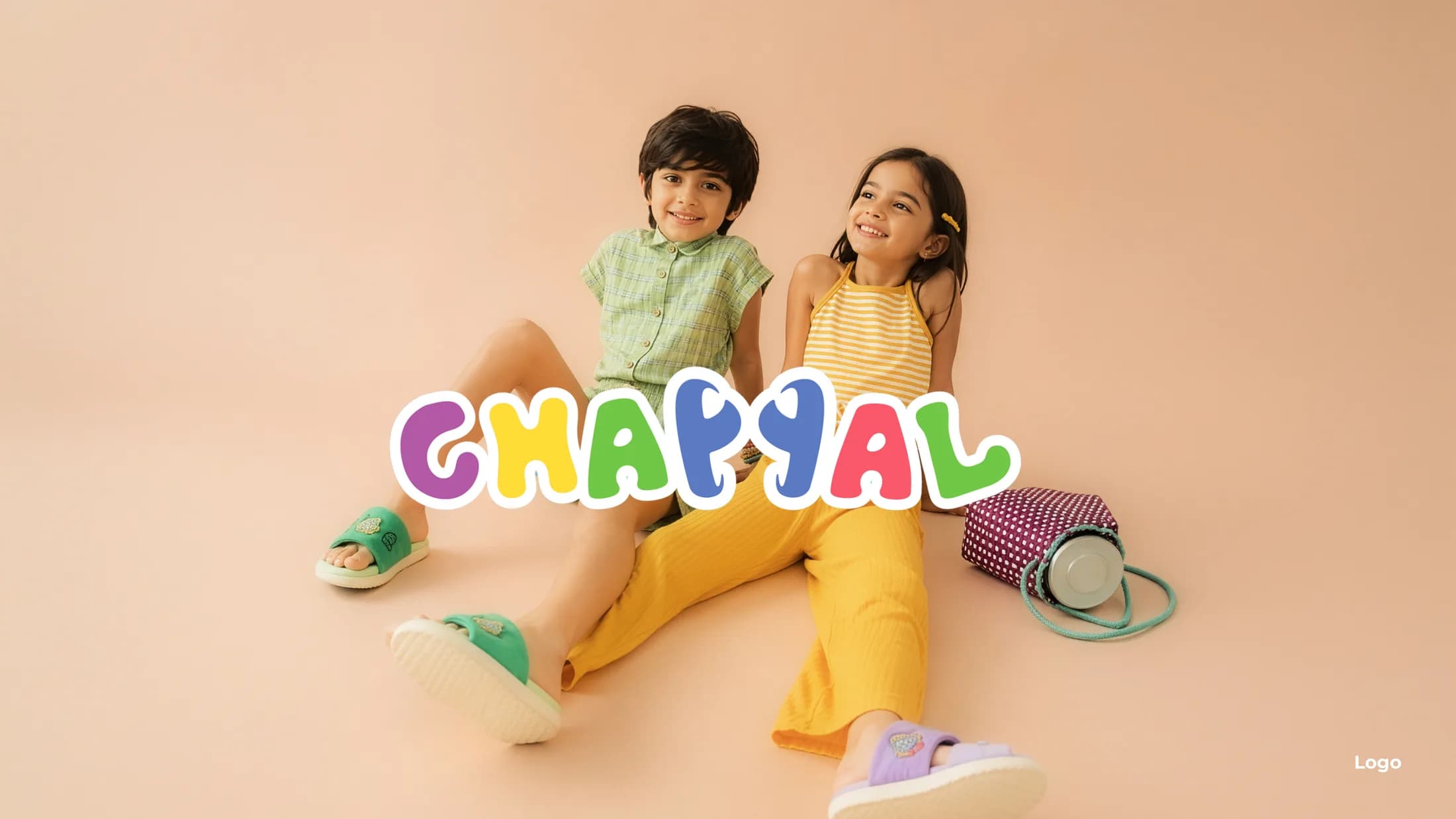 Two kids in colorful Chappal outfits against a peach backdrop
